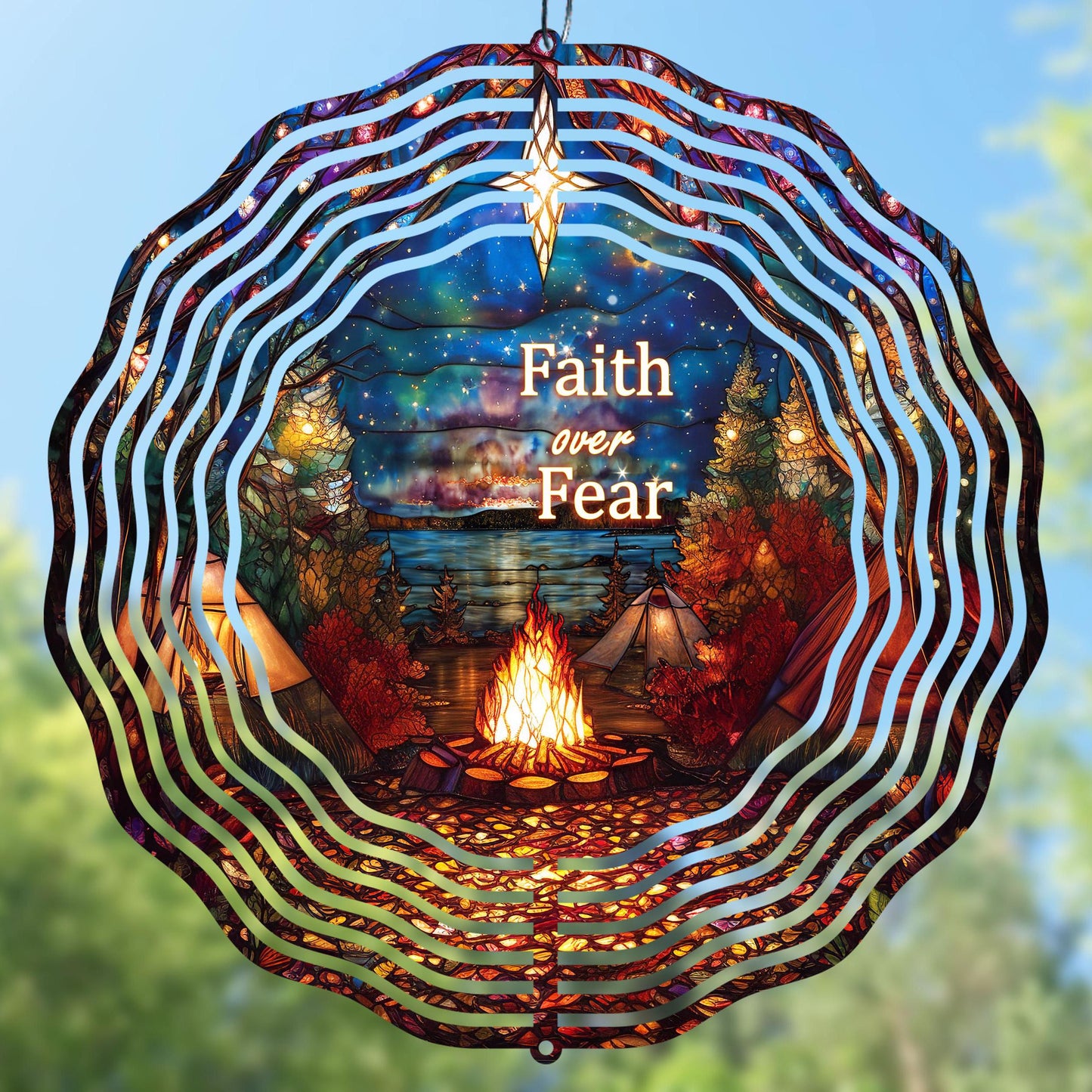 Decorative wind spinner with 'Faith over Fear' text, campfire, and tents against a night sky.